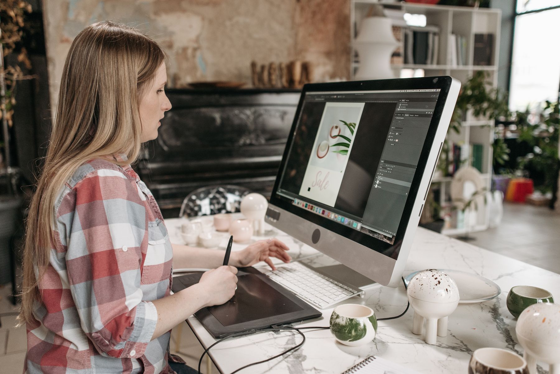A designer creates digital artwork with a graphics tablet at a studio desk.