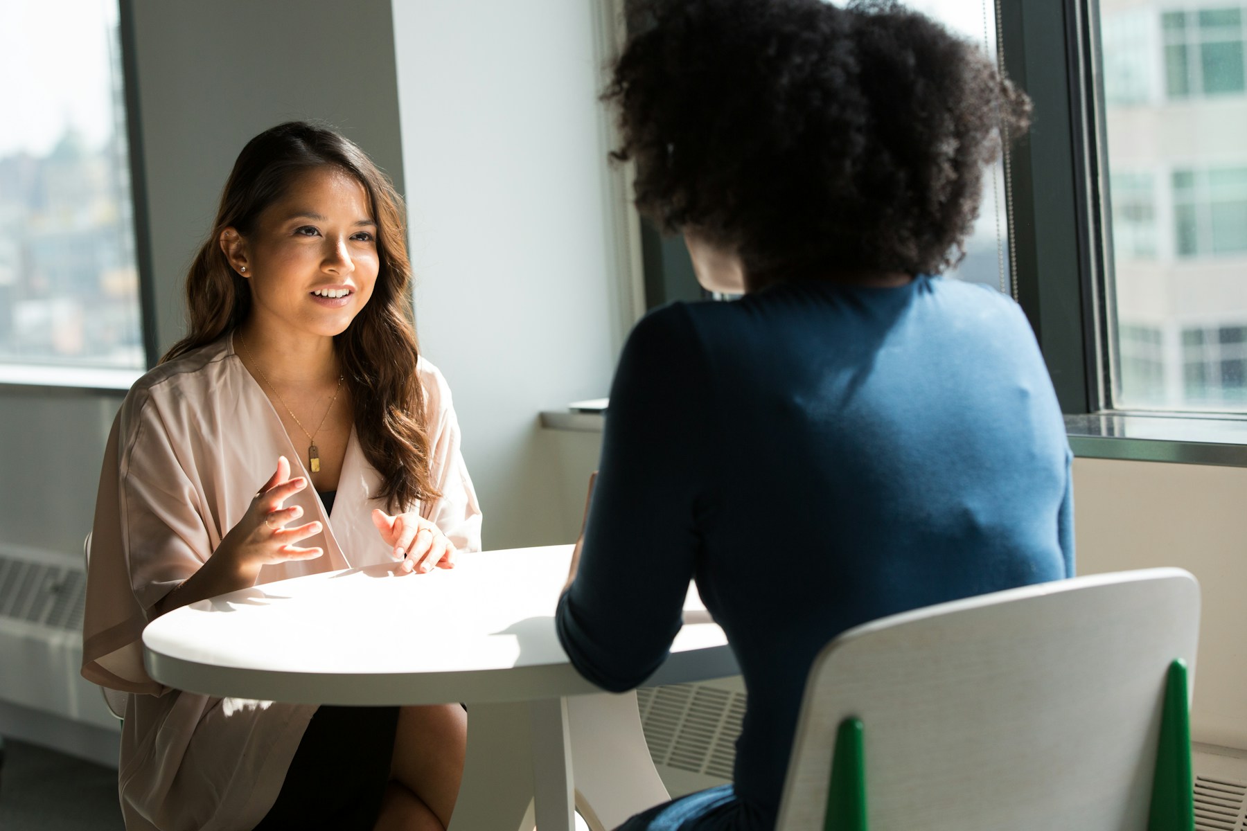 Two professionals discussing a project at a bright meeting table.