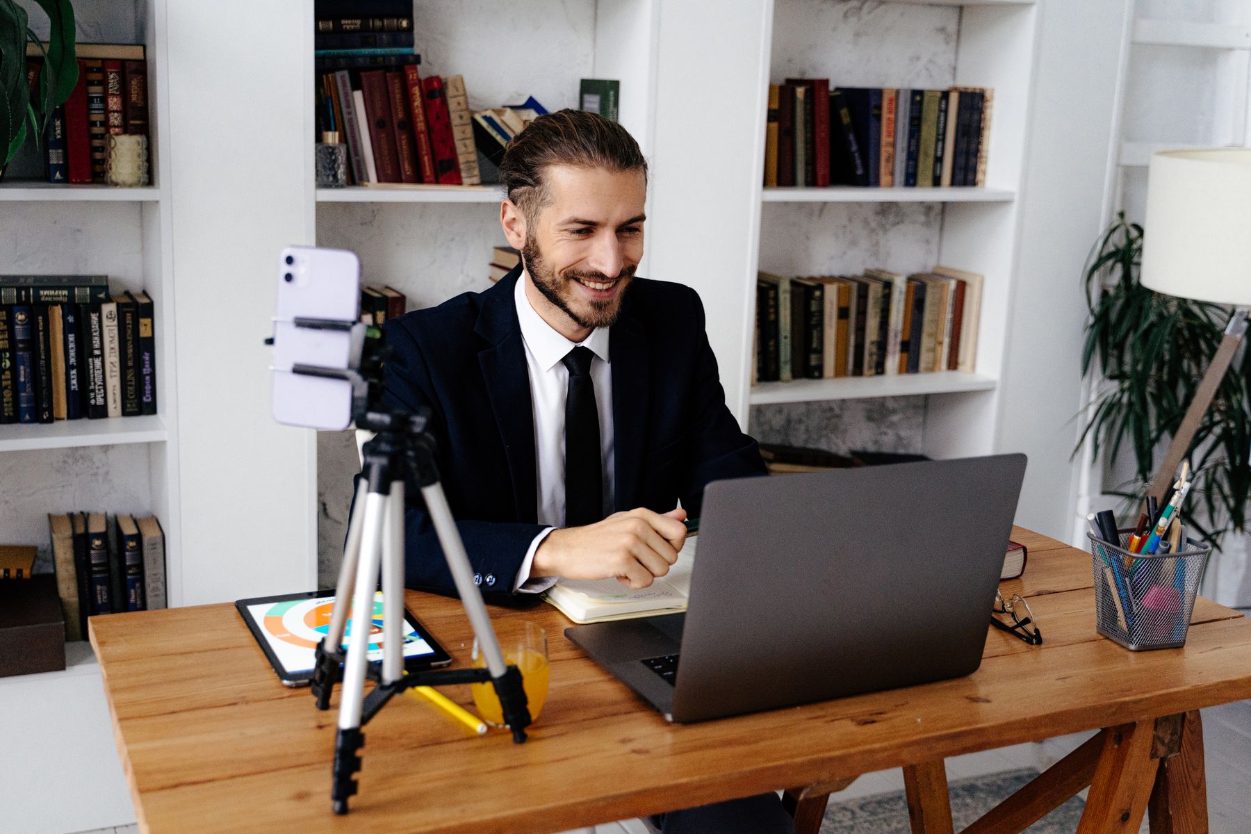 A professional hosts a video conversation from a desk with a laptop and camera.