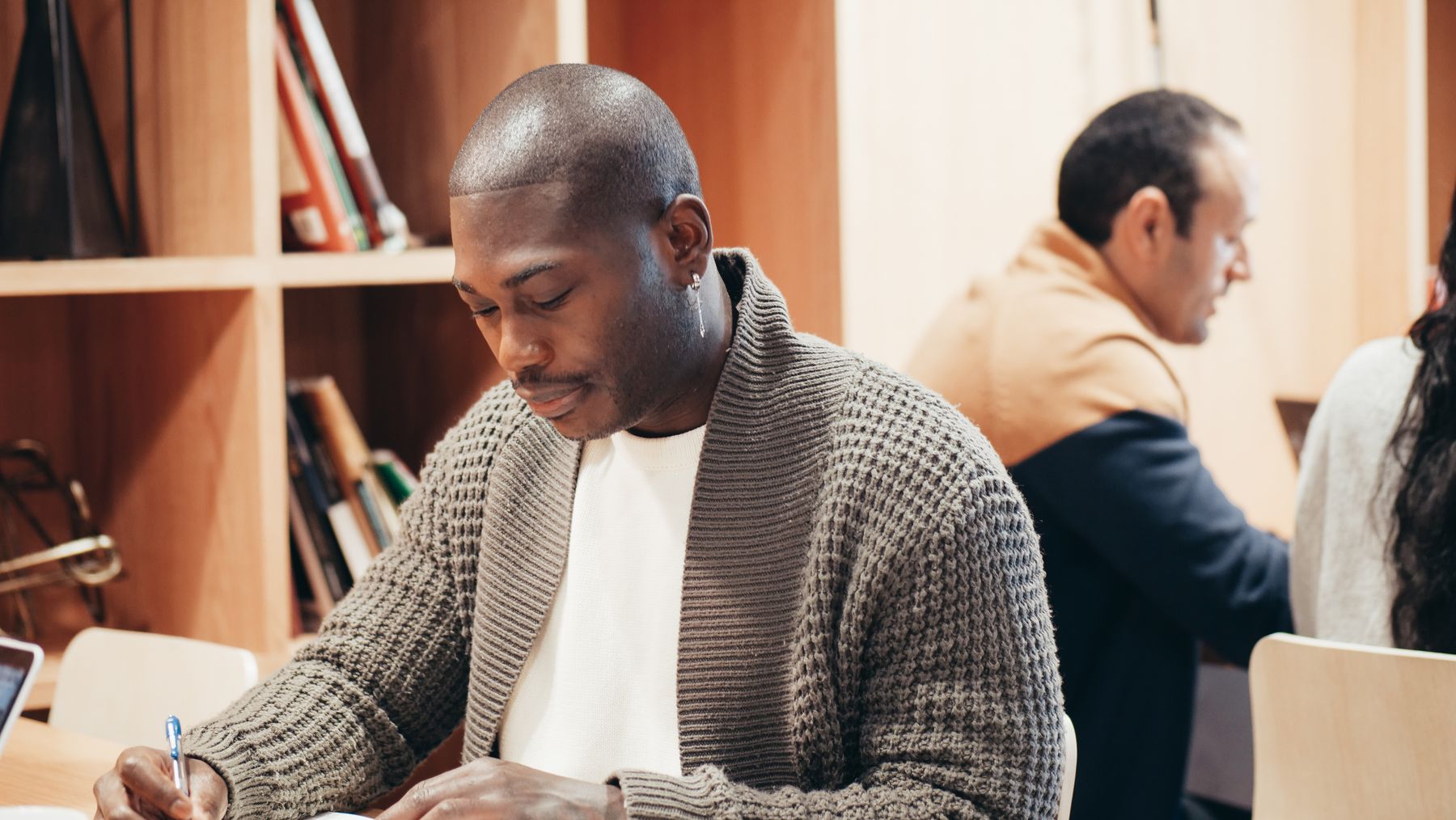 An adult learner takes notes while studying in a quiet shared workspace.