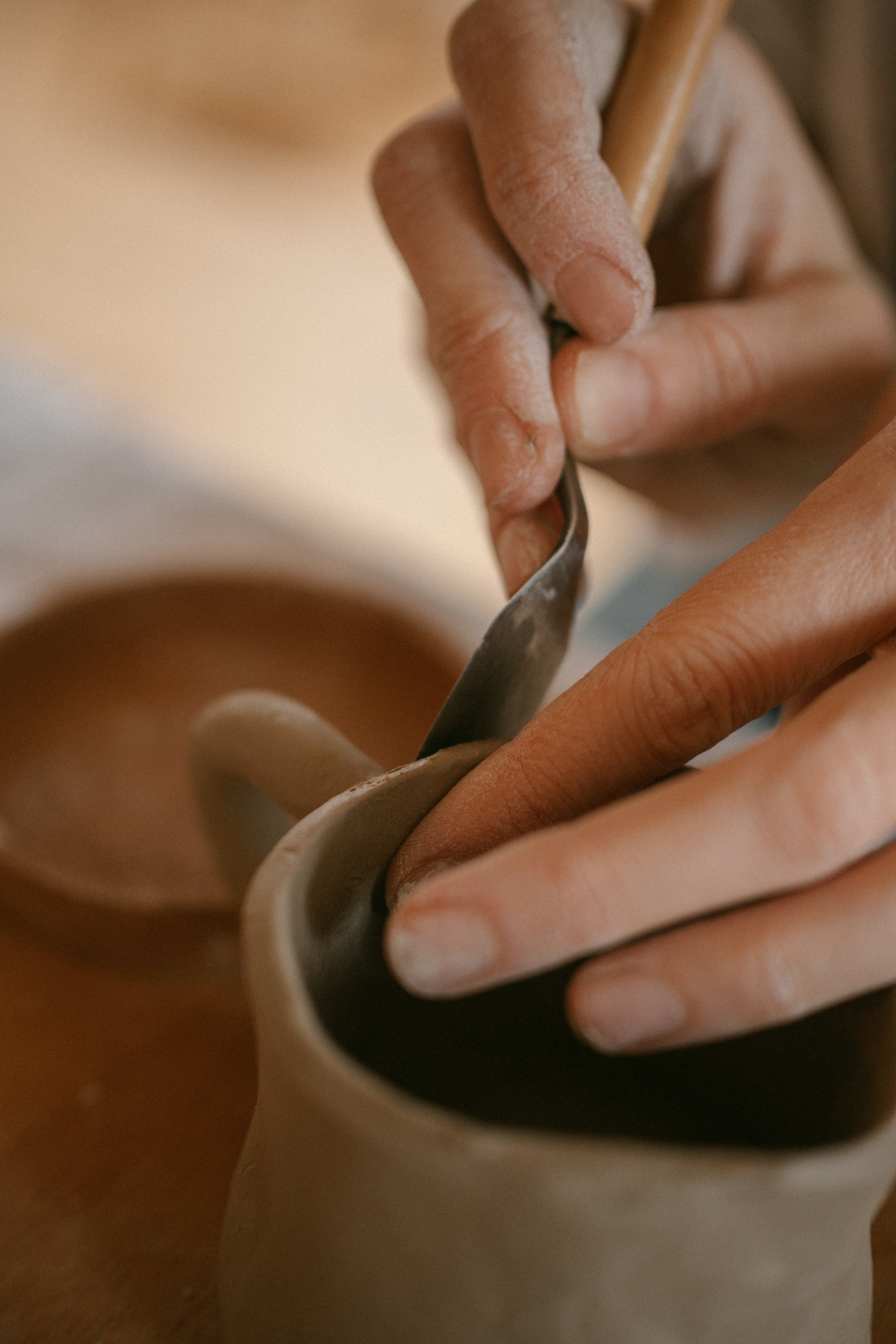 Hands shaping a ceramic piece in a maker’s studio