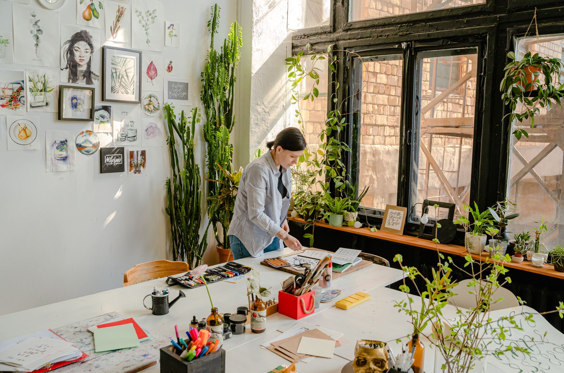 An artist working in a bright, plant-filled studio
