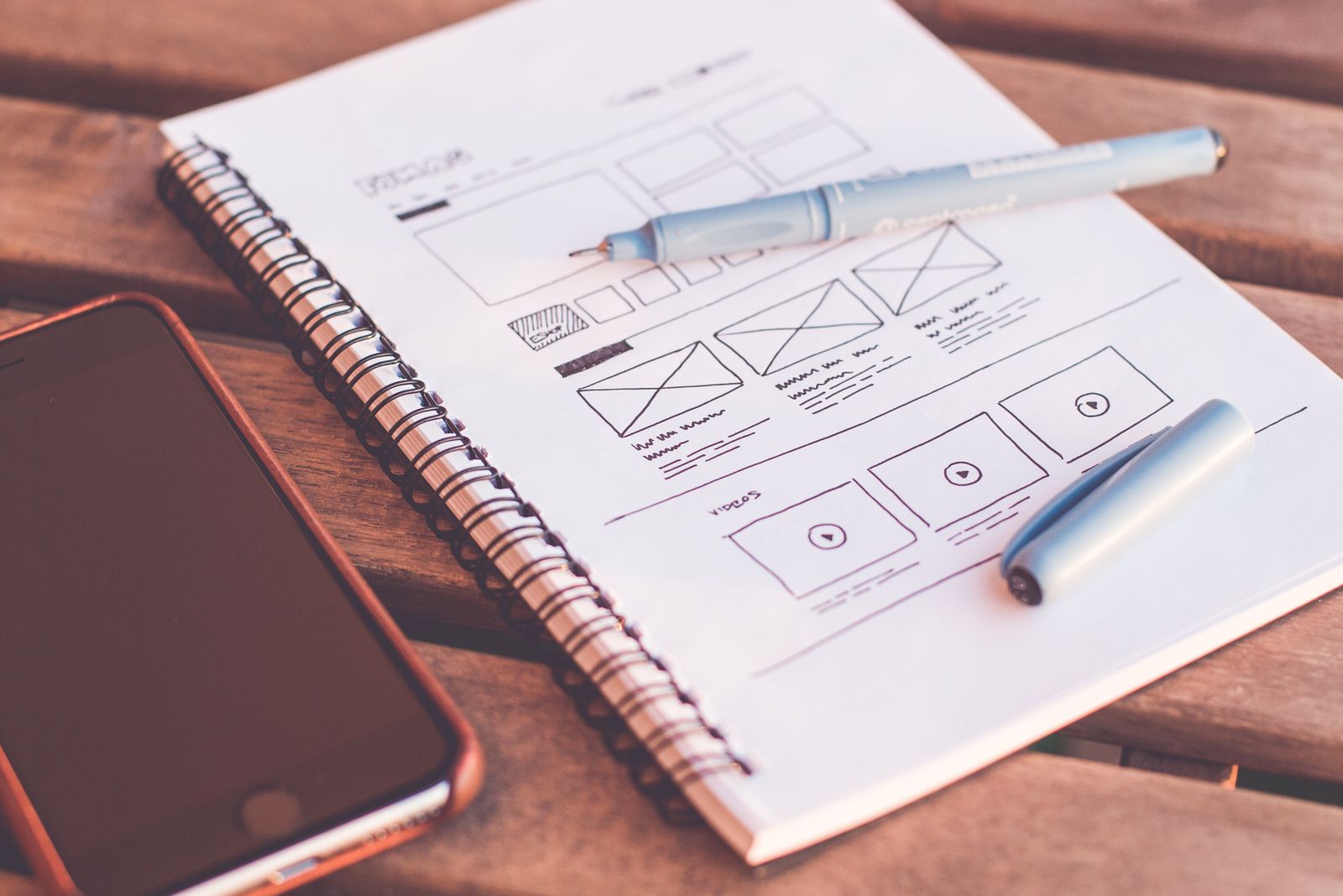 Website wireframes, page layouts, and design resources arranged on a desk